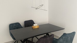 A modern dining area with a rectangular table, four chairs, and a unique pendant light.