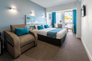 A hotel room with a bed, a sofa, a desk, a chair, a TV, and a painting on the wall. - Best Western Hotel Royan Ocean (Royan)