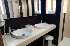 Een badkamer met twee wasbakken, een spiegel, een handdoekhouder en een douche.