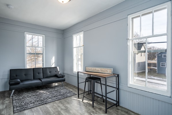 A room with a black leather sofa, a small wooden table with a sign, and a patterned rug. - This property is conviently located in Lakeside, within minutes from the Lake. (Muskegon)