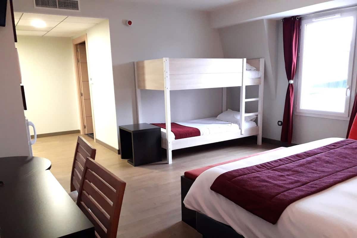 A hotel room with bunk beds, a desk, and a chair.