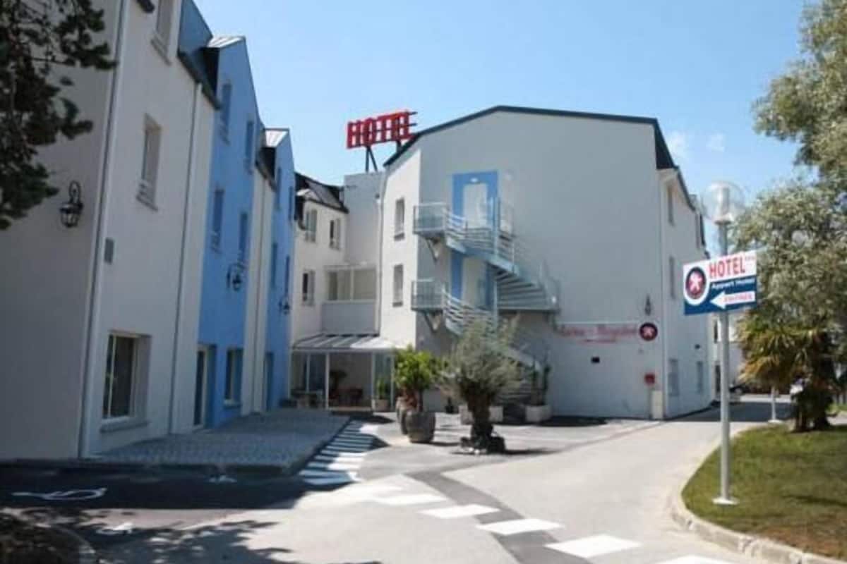 A hotel with a blue and white facade, a visible entrance, and a staircase leading to the entrance.