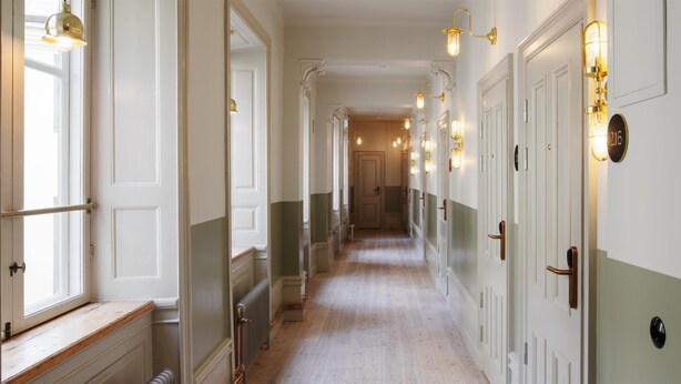 A hallway with doors, a radiator, and wall-mounted light fixtures. - Best Western Plus Hotel Frantz (Stockholm)