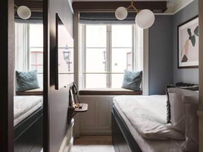 A bedroom with two beds, a window seat with a lamp, and a framed picture on the wall. - Best Western Plus Hotel Frantz (Stockholm)