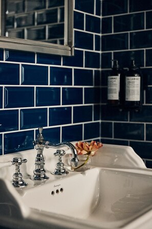 A bathroom with a white sink, a mirror above it, and blue-tiled walls. - Best Western Plus Hotel Frantz (Stockholm)