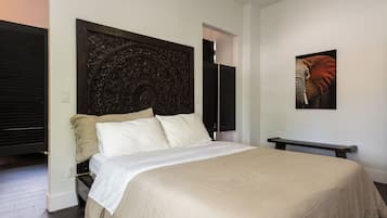 Une chambre à coucher avec un grand lit, une tête de lit décorative, une table de chevet et une œuvre d’art accrochée au mur.