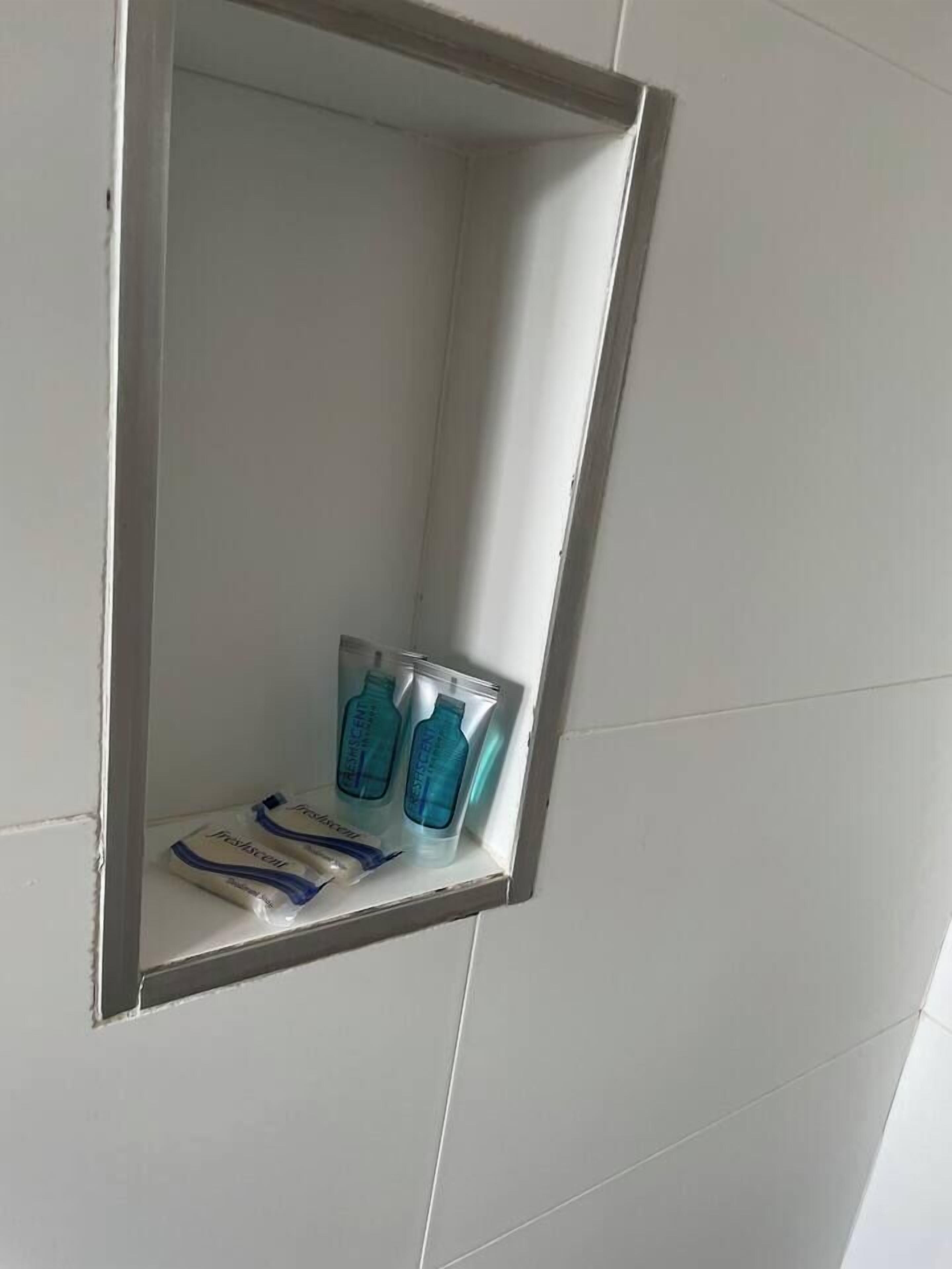 A bathroom with a mirror, two bottles of hand soap, and two packets of tissues.