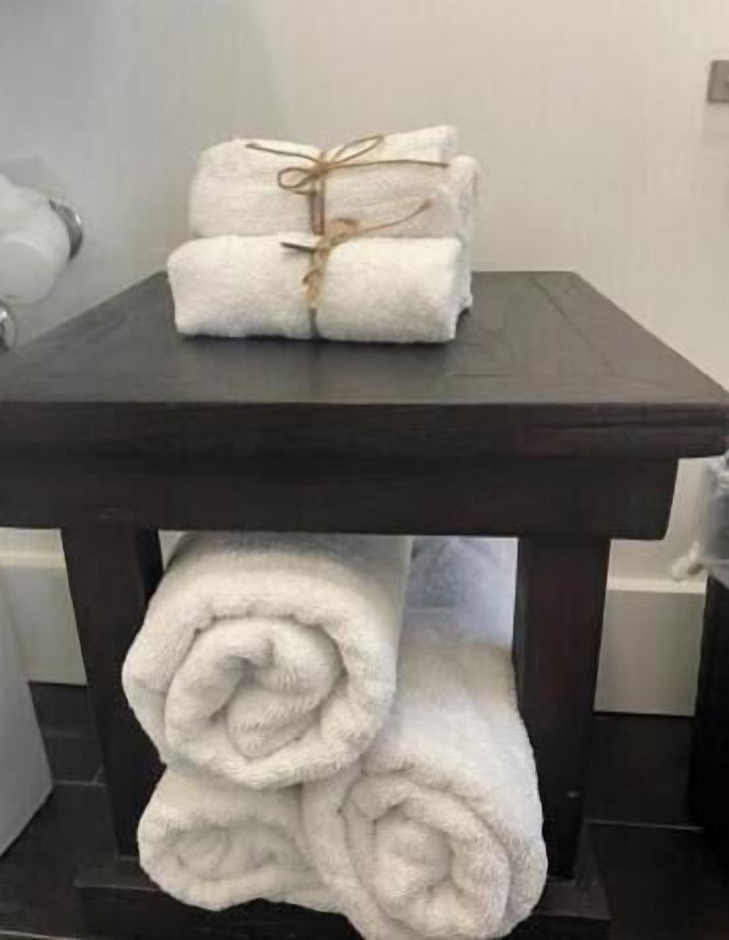 A dark wooden table with two neatly folded white towels tied with a string.