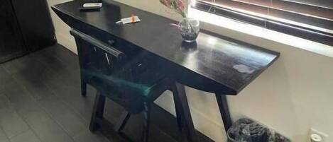 Une cuisine avec un plan de travail foncé, un vase rempli de fleurs et une poubelle.