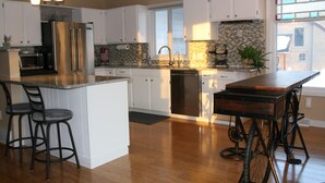 Una cocina moderna con armarios blancos, electrodomésticos de acero inoxidable y una isla central con taburetes de bar.