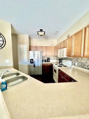 Enjoy cooking in this well-equipped kitchen with a stainless steel refrigerator, double sink, and microwave.