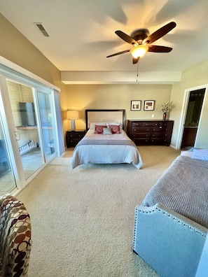 Relax in this serene bedroom with a comfortable bed, dresser, and sliding glass door leading to a balcony.