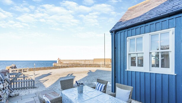 A patio with wicker furniture and a table, overlooking a beach and a lighthouse. - 2 bedroom accommodation in Banff (Banff)