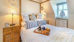 A bedroom with a wooden headboard, two bedside tables with lamps, a bed with a tray of breakfast, and a window with curtains. - 2 bedroom accommodation in Banff (Banff)