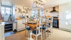 A modern kitchen with white cabinetry, a wooden dining table, and a black stove. - 2 bedroom accommodation in Banff (Banff)