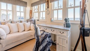 A room with a large window, a desk, a sofa, and a painting on the wall. - 2 bedroom accommodation in Banff (Banff)