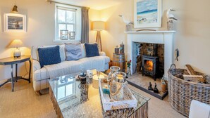 A cozy living room with a fireplace, a sofa, a coffee table, and a lamp. - 2 bedroom accommodation in Banff (Banff)