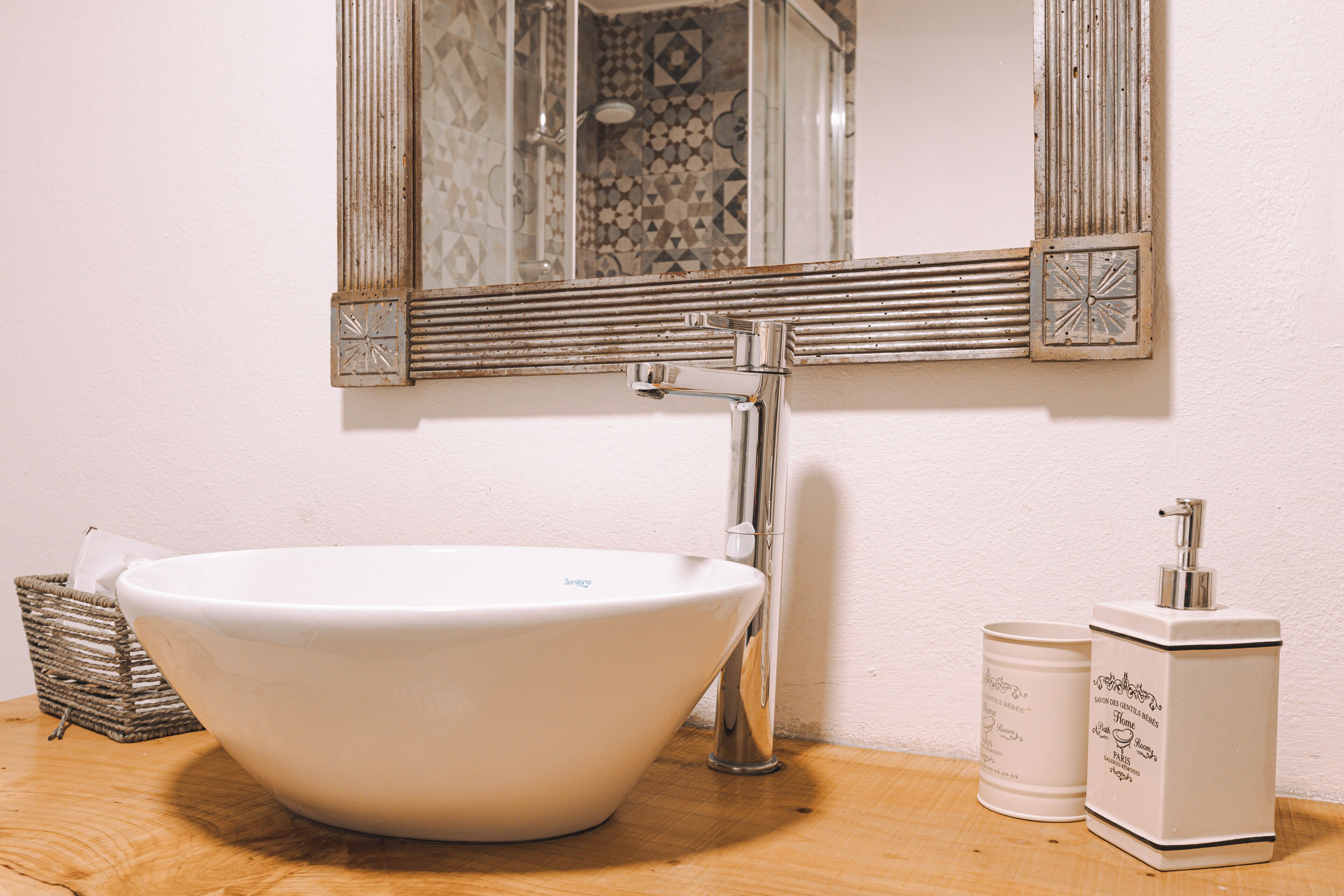 Une salle de bain avec un lavabo blanc, un miroir et un distributeur de savon.