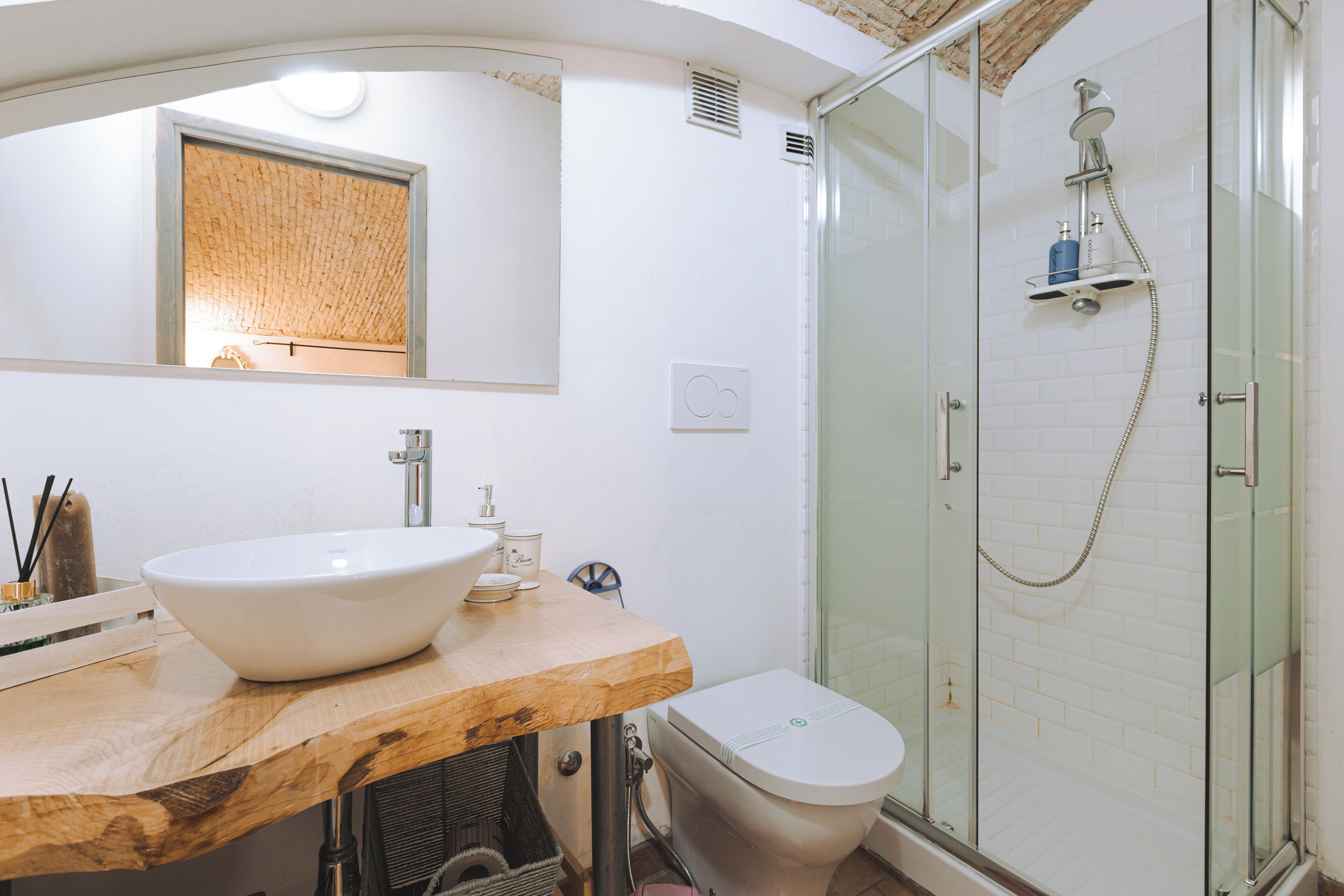 Une salle de bain moderne avec un meuble-lavabo en bois, un grand miroir, un lavabo blanc, des toilettes et une douche à parois de verre.