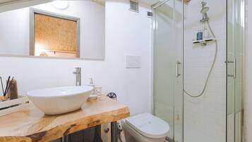 Une salle de bain moderne avec un meuble-lavabo en bois, un grand miroir, un lavabo blanc, des toilettes et une douche à parois de verre.
