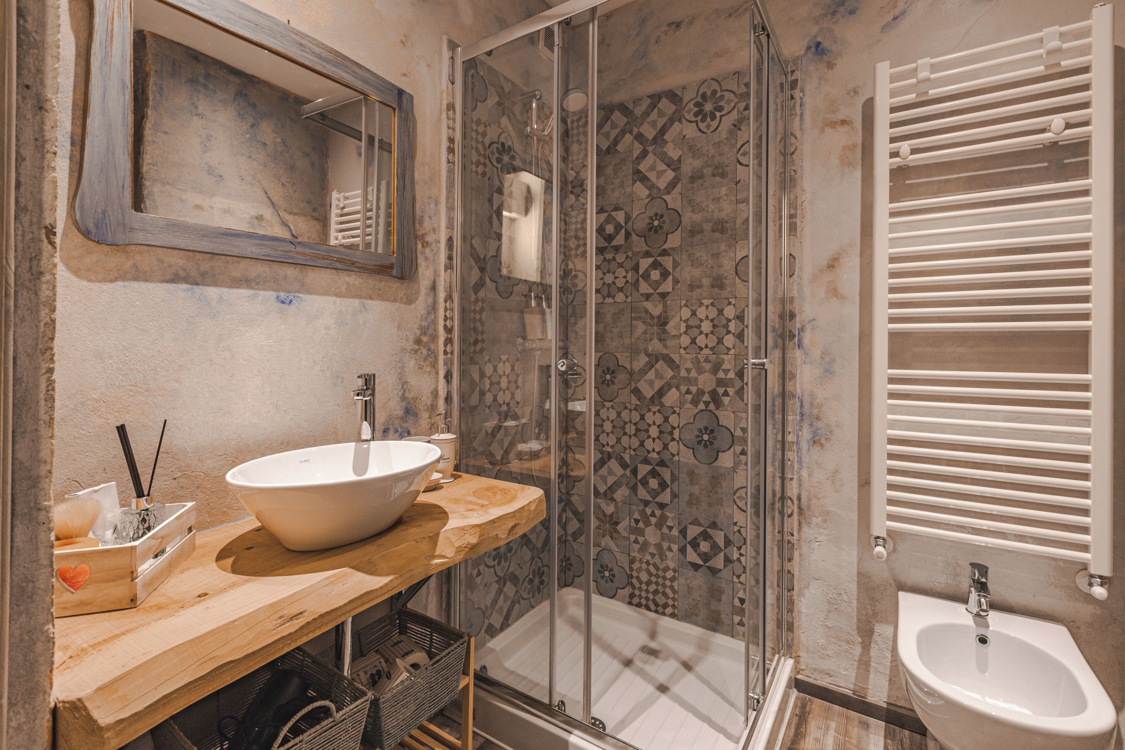 A bathroom with a wooden vanity, a large sink, a glass shower enclosure, and a bidet.