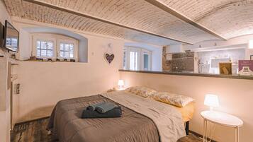 Ein Schlafzimmer mit einem großen Bett, einem Nachttisch mit Lampe, einer herzförmigen Dekoration an der Wand und einem Fenster mit Blick ins Freie.