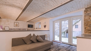 A modern living room with a sofa, a television, and a large window. - Trieste Art Loft (Trieste)