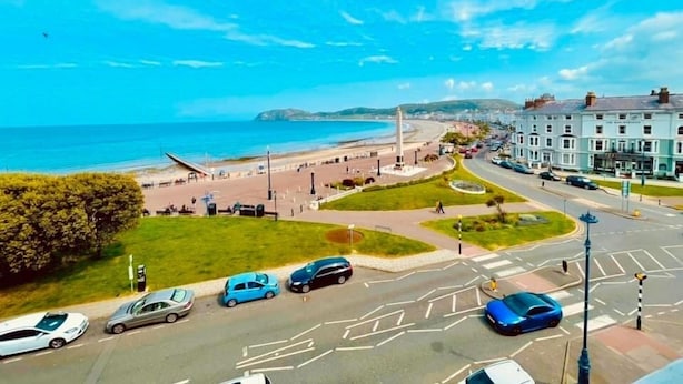 A coastal road with a roundabout, a beach, and buildings in the background. - Lawton & Lauriston Court (Llandudno)