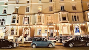 A row of multi-story buildings with a prominent entrance featuring a sign. - Lawton & Lauriston Court (Llandudno)