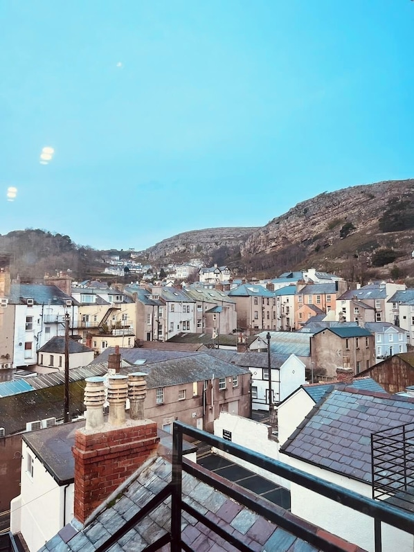 A residential area with terraced houses, a prominent hill in the background, and a clear sky. - Lawton & Lauriston Court (Llandudno)
