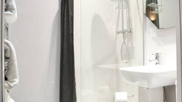 A modern bathroom with a glass shower enclosure, a white sink, and a toilet.