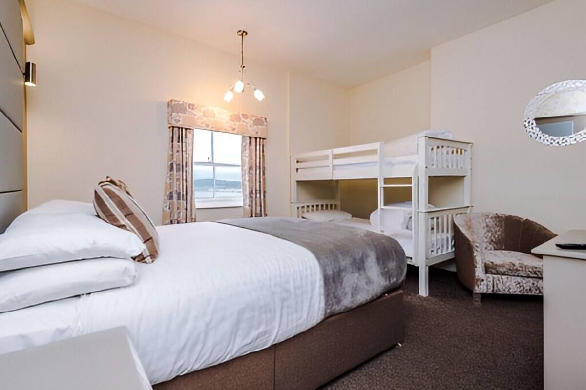 A bedroom with a large bed, bunk beds, a chair, and a desk.