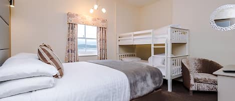 A bedroom with a large bed, bunk beds, a chair, and a desk.