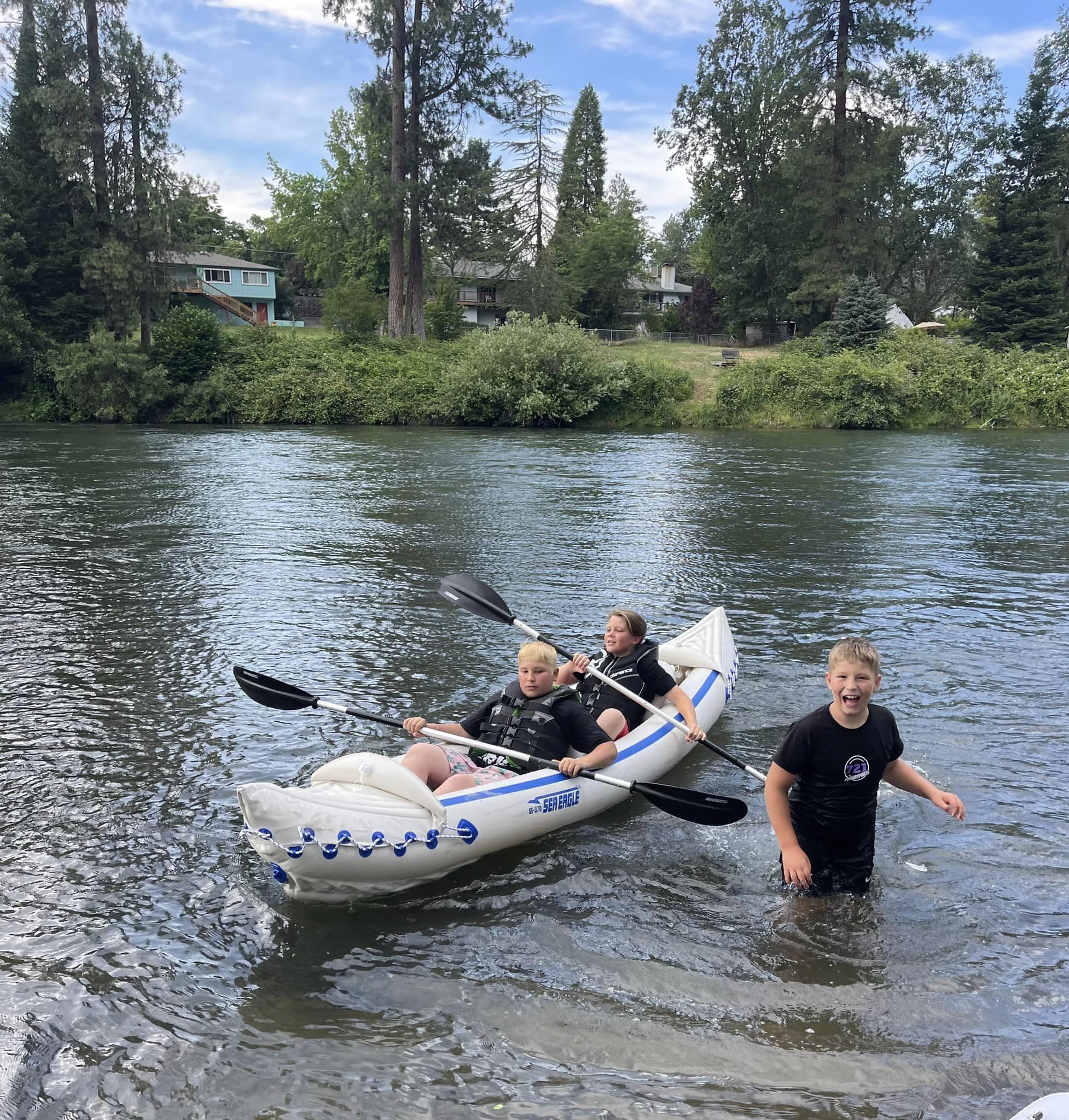 Eine Gruppe von Menschen in einem weißen Schlauchboot mit blauen Akzenten auf einem Fluss.