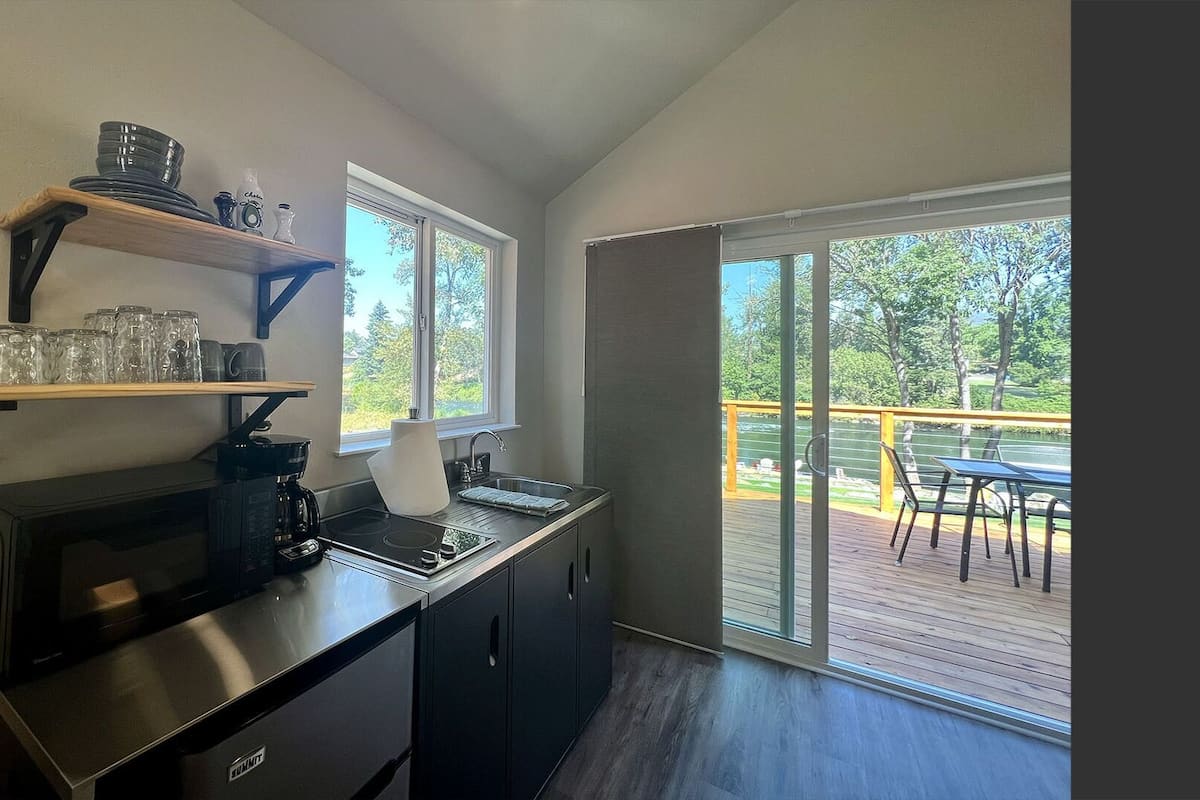 A compact kitchen with a coffee maker, a sink, and a window overlooking a deck.