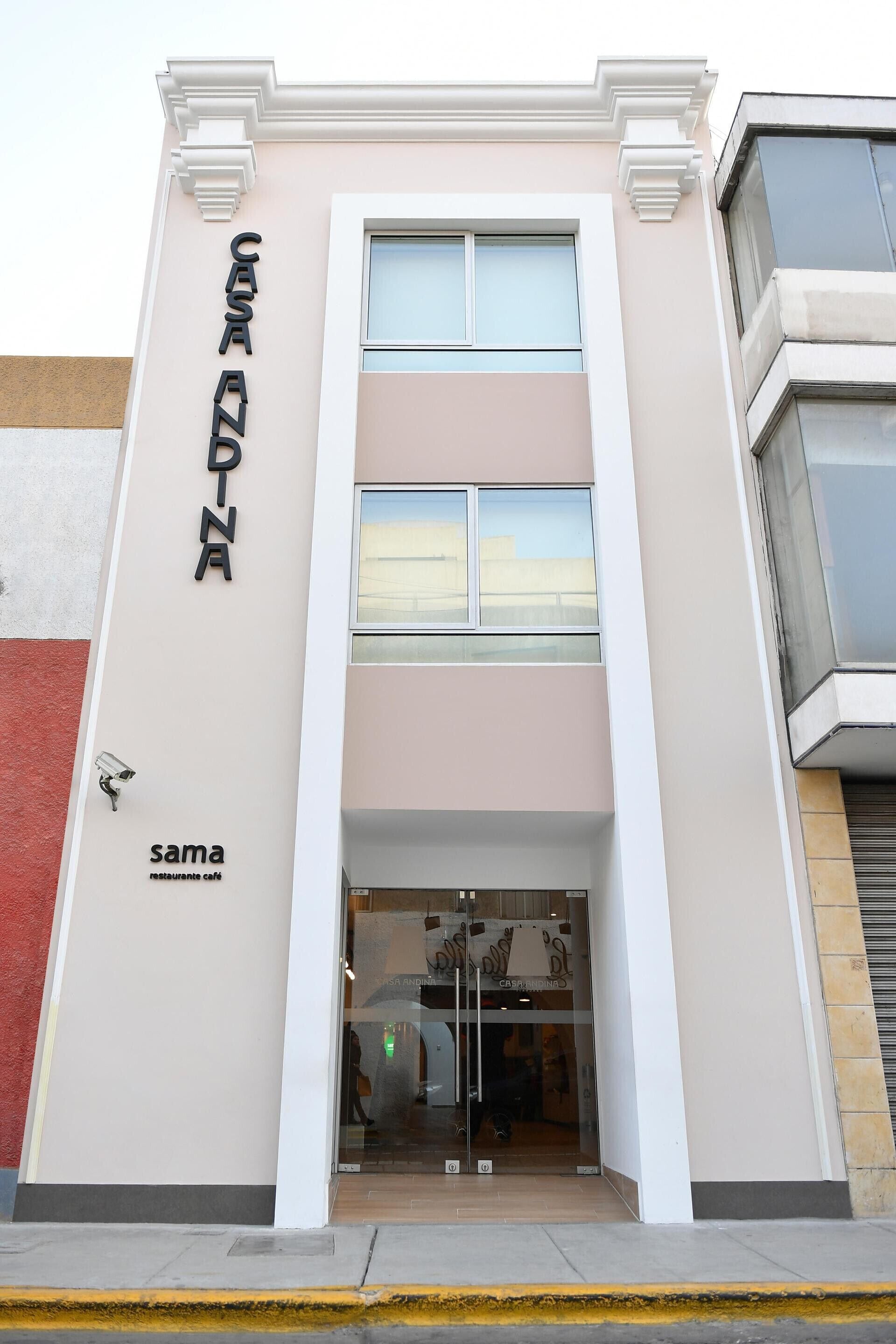 Un edificio con un letrero que dice 'CASA ANDINA' y un café llamado 'sama' debajo.