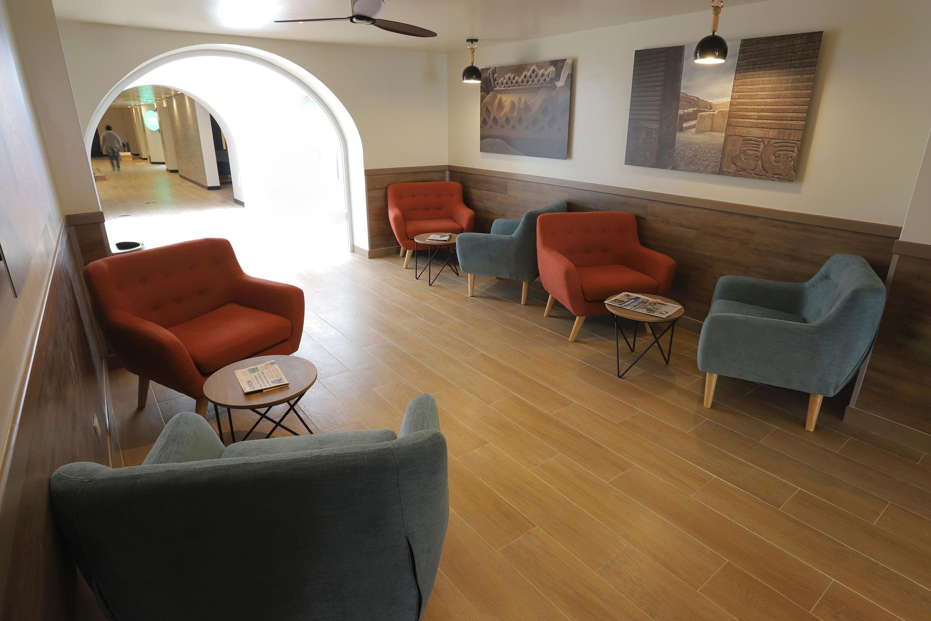 A lobby with a seating area featuring armchairs and a coffee table, a ceiling fan, and artwork on the walls.