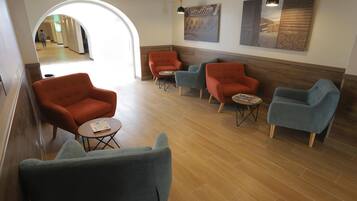 A lobby with a seating area featuring armchairs and a coffee table, a ceiling fan, and artwork on the walls.