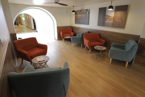 A lobby with a seating area featuring armchairs and a coffee table, a ceiling fan, and artwork on the walls. - Casa Andina Standard Trujillo Plaza (Trujillo)