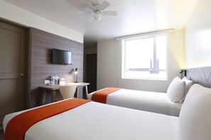 Habitación de hotel con dos camas, un escritorio, un televisor y una ventana.