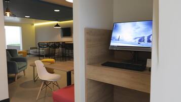 A modern office space with a desk, computer, and seating area.