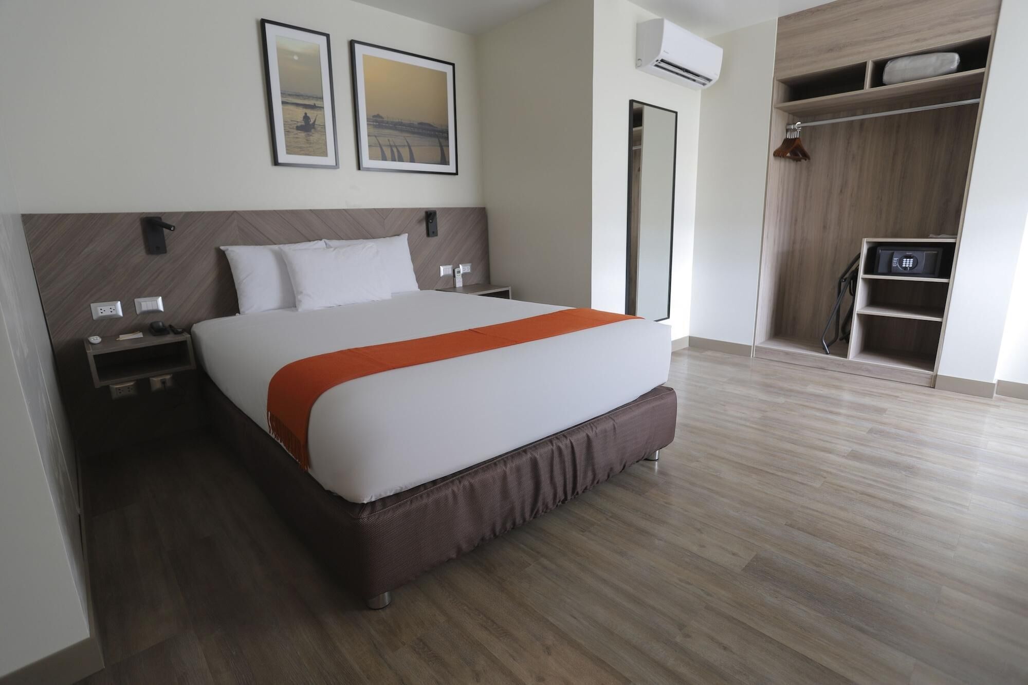 Una habitación de hotel con cama, mesitas de noche, armario y espejo.
