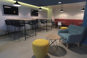 A modern lounge area with a bar, seating, and a TV screen. - Casa Andina Standard Trujillo Plaza (Trujillo)