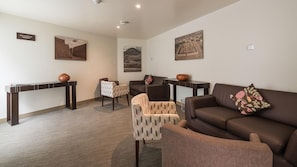 A modern living room with a brown sofa, patterned armchairs, a coffee table, and a console table with decorative vases. - Casa Andina Standard Trujillo Plaza (Trujillo)