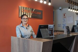 Un mostrador de recepción con un cartel que dice 'CASA ANDINA STANDARDS' y una computadora Lenovo encima.