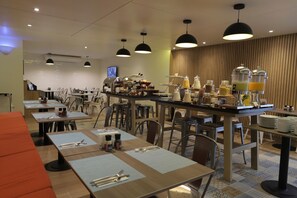 A hotel dining area with multiple tables, chairs, and a buffet bar with various food and drink options. - Casa Andina Standard Trujillo Plaza (Trujillo)