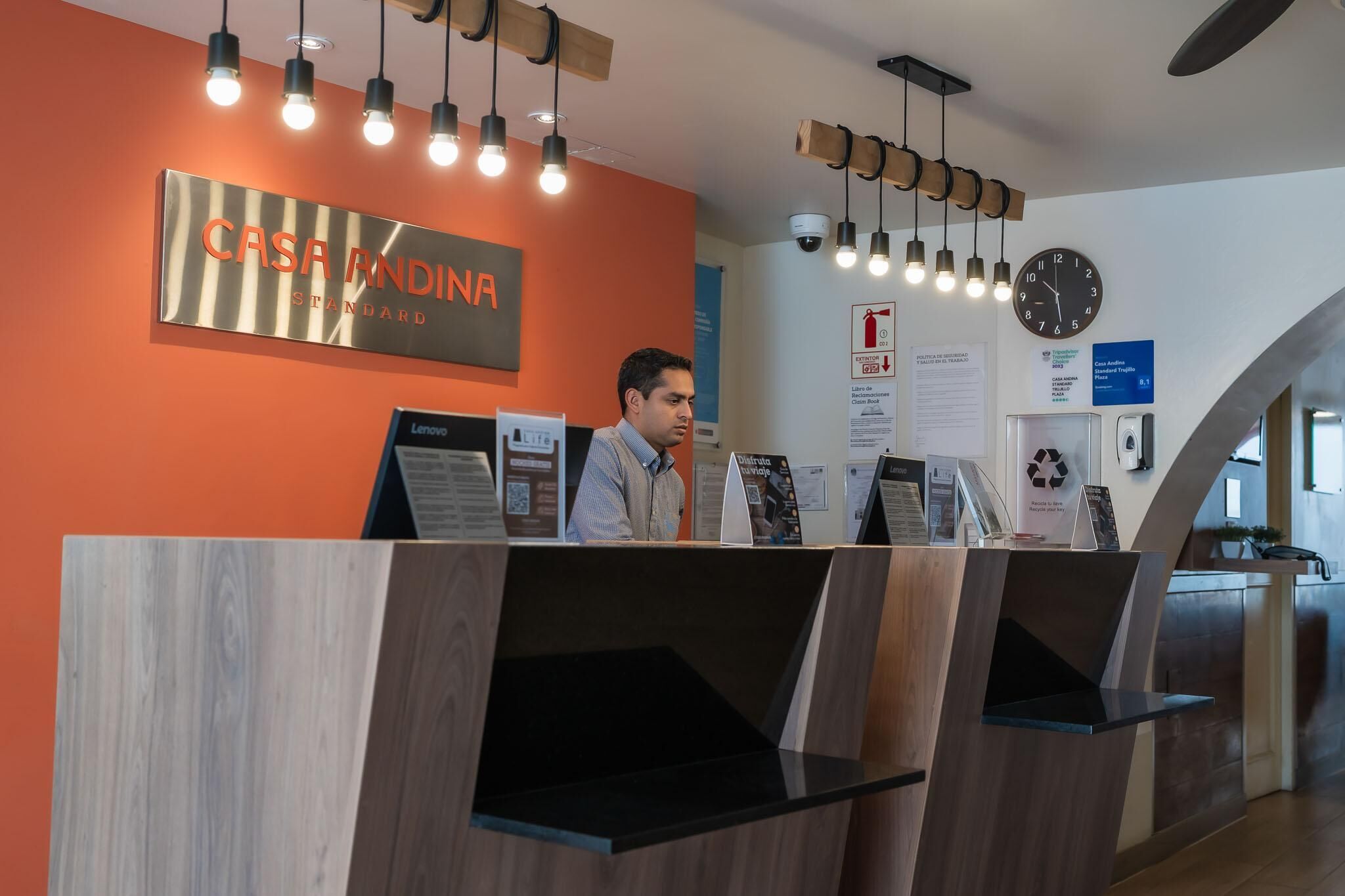 A reception desk with a sign reading 'CASA ANDINA STANDARD' and a clock on the wall.
