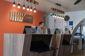 Un mostrador de recepción con un letrero que dice 'CASA ANDINA STANDARD' y un reloj en la pared.