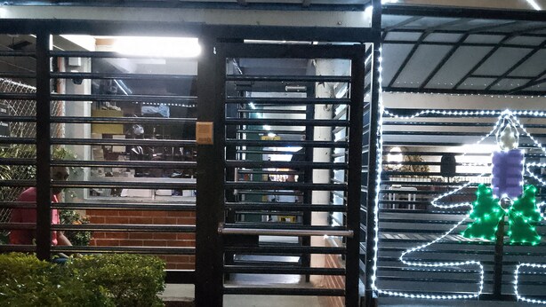 A covered entrance with a metal gate, a staircase leading inside, and a Christmas tree decoration with lights. - El Confort (Cali)