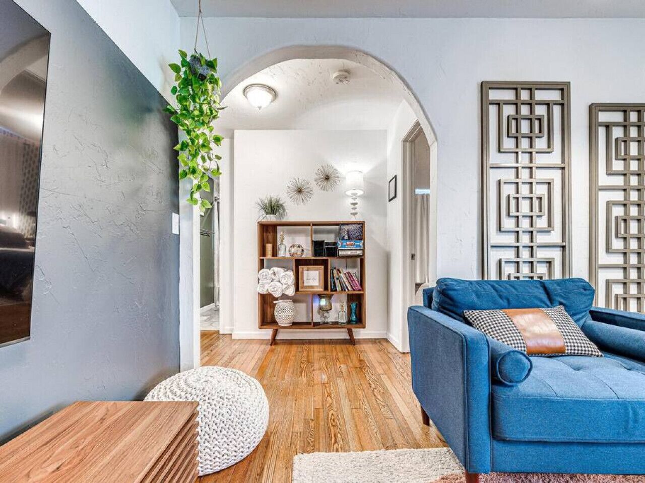 A modern living room with a blue sofa, wooden coffee table, and a decorative bookshelf.